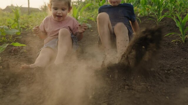 Brother and sister playing together, shaking their feet on the ground. Countryside lifestyle. Concept of grounding and connecting with nature.