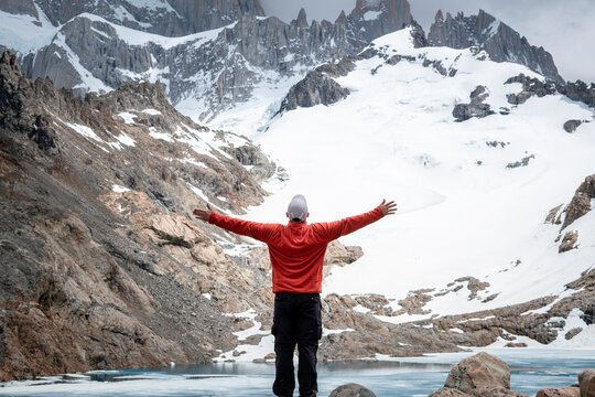 Hombre feliz festejando de haber llegado a la laguna de los tres, al pie del cerro Fitz Roy, recorrido de senderismo en el Chalten, Patagonia Argentina