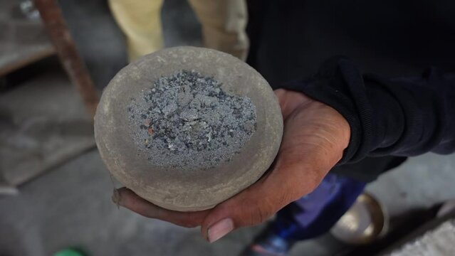 A worker displays ashes for making copper and brass household items.