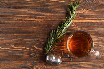 Glass cup of hot rosemary tea on wooden background