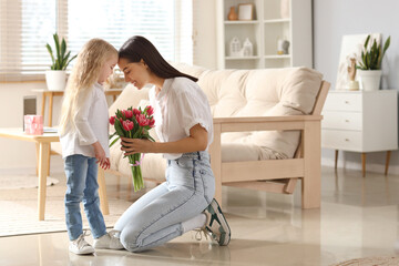 Little girl congratulating her mom with bouquet of flowers at home. Mother's Day celebration