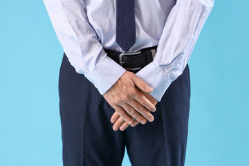 Young businessman with prostate problem on blue background, closeup. Cancer awareness concept