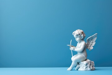 Figurine of angel Cupid on the podium with a bow and arrow on a blue background, copy space, Valentine's day, Mother's day, Women's Day and love concept