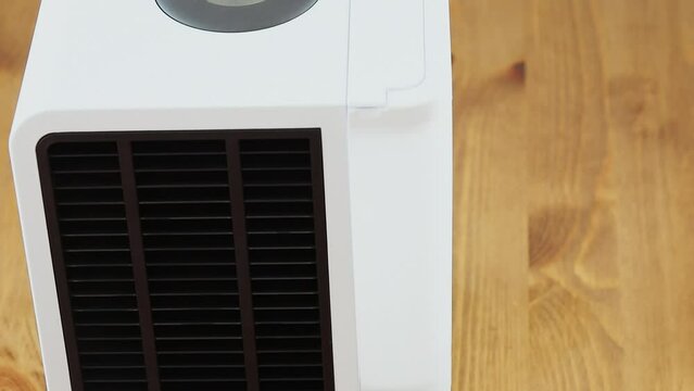 Air humidifier with black lattice rotates on wooden floor