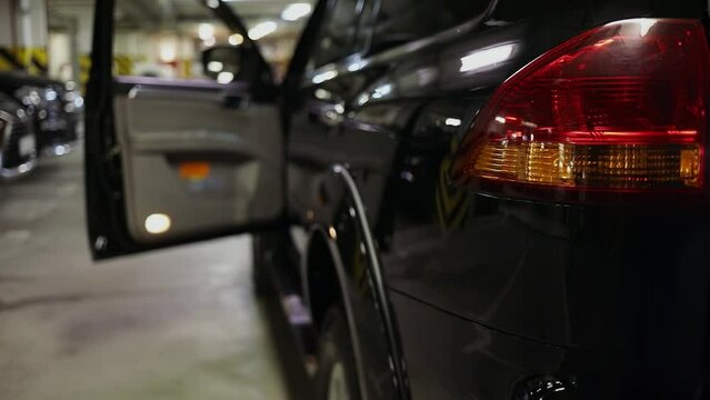 Shiny black car with opened drivers door is on underground parking