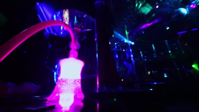 Smoke goes from water pipe with colorful light during strip dance performance in night club. Slow motion