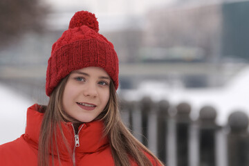 Portrait of a girl smiling in a red hat on a background of the winter landscape