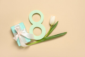 Figure 8 made of paper with beautiful white tulip and gift box on beige background. International Women's Day