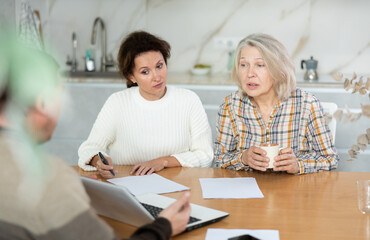 Fototapeta premium Mother and daughter considering offer from agent, asking questions and signing papers