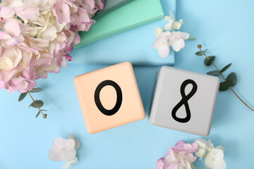 Cube calendar with date 08, beautiful hydrangea flowers and notebooks on blue background. International Women's Day