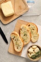 Tasty baguette with garlic and dill served on light grey table, flat lay