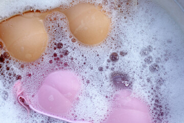 Lady bra soaked in water dissolved detergent with white foam bubble. Laundry concept