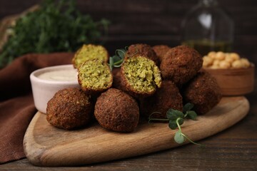 Delicious falafel balls and sauce on wooden table