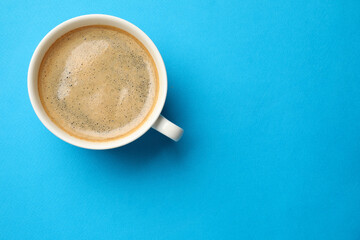 Aromatic coffee in cup on light blue background, top view. Space for text