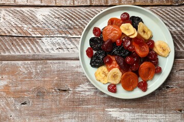 Mix of delicious dried fruits on wooden table, top view. Space for text
