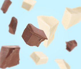 White and milk chocolate chunks on light blue background