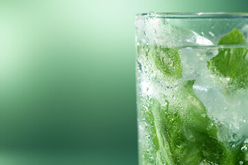 Cool drink with ice mint and lime close-up on green background