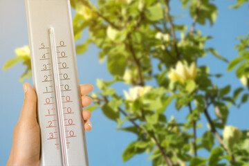 Woman holding thermometer outdoors in spring, closeup