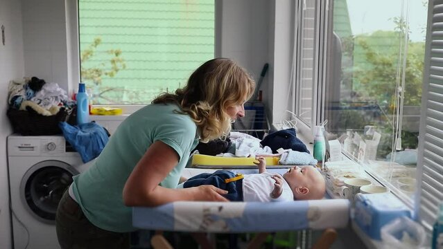 Mother talks with baby which lies on table. Slow motion
