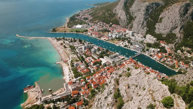 Aerial view of Omis town by the sea with Cetina river winding through it. Summer vacation in Croatia.