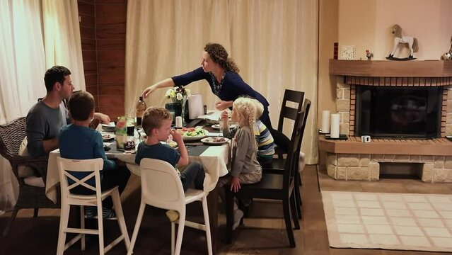 two Parents and four children dinner in room near fireplace. Slow motion