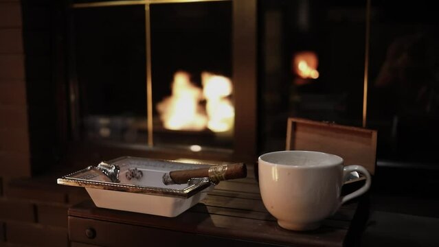 White cup of coffee, burning cigar on ashtray at wooden table