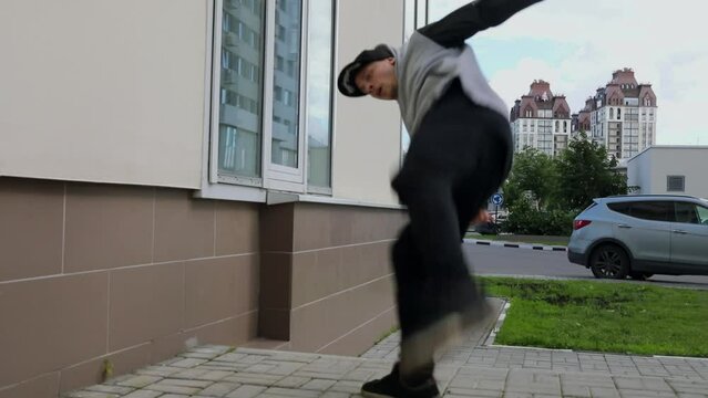 Young man runs and makes somersault during extreme parkour training on street. Slow motion