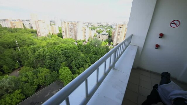 Young man does back flip on balcony of tall house in city. Slow motion