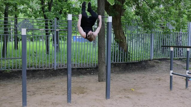 Man makes exercises on bar among trees. Slow motion