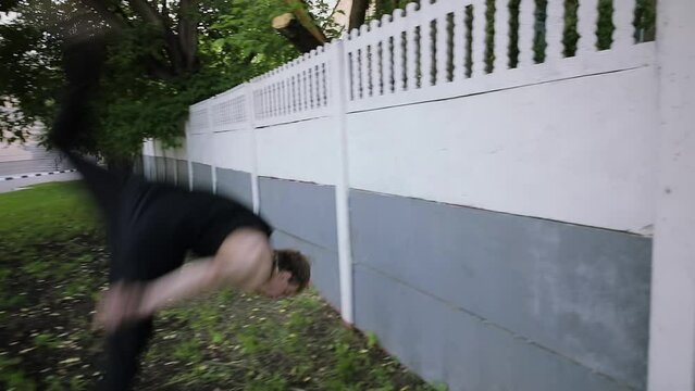 Man pushes off from wall and makes somersault. Slow motion