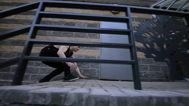 Young man runs up by staircase near wall. Slow motion