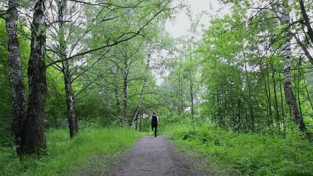 Young man jumps from out of frame and runs by alley in park