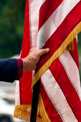 Vertical close-up of male hand holding an American flag commemorating Memorial Day in the United States of America.