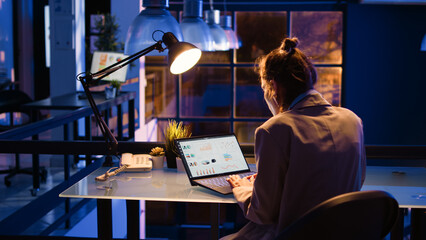 Startup worker checking financial data report online with diagrams late at night, helping to increase profit. Female entrepreneur working on economy investment with statistics. Handheld shot.