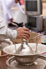 Man holding a silver tea pot at the Souq Al-Zal.