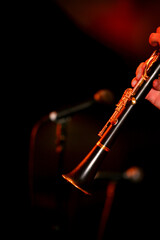 Vertical close-up of musician's fingers playing a clarinet with blurred out microphones in the...