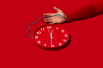Conceptual image of arm wired to clock on red background