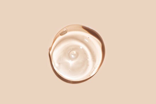 Swirling liquid foundation drop isolated on beige
