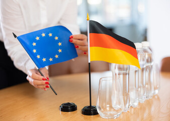 Little flag of Germany on table with bottles of water and flag of European Union put next to it by...
