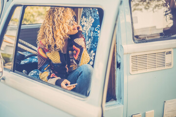 Attractive woman with blond curly hair looks out the window of her van. spring, nature and travel...