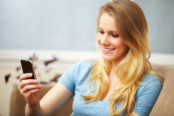 Fototapeta na wymiar Young Woman with a Smart Phone on Sofa