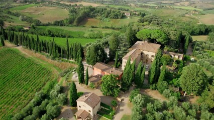 Aerial drone footage captures the breathtaking summer vista of an elegant villa nestled amidst the scenic beauty of Tuscany, Italy.