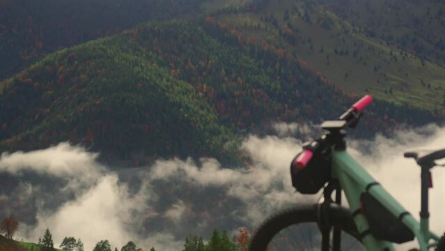 Electric bike stands on high mountain above clouds in autumn in Bavarian Alps. Brightly colored mountain e bike against German alps in higher than clouds. Theme travels in alpine by eletro cycle. 
