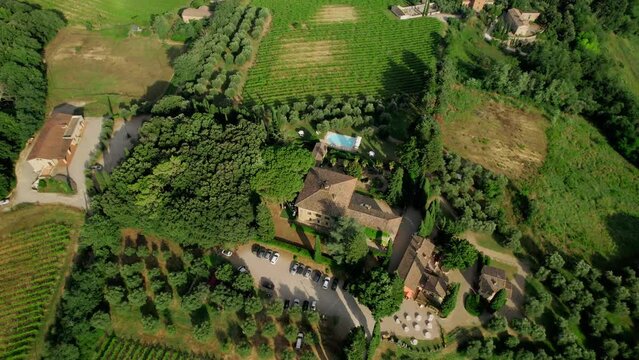 Aerial drone footage captures the breathtaking summer vista of an elegant villa nestled amidst the scenic beauty of Tuscany, Italy.