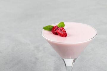 Valentine's Day dessert. Raspberry cream Panna Cotta. In martini glass. Light gray background....