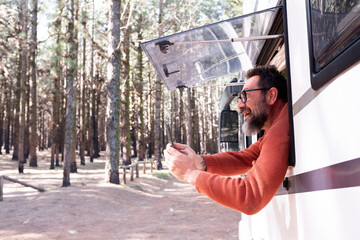 One man enjoying the view outside the window of a motorhome camper van enjoying vanlife and alternative travel vehicle vacation holiday. Freedom. Nomadic lifestyle people fulltimers. Free parking van