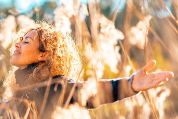 One happy woman outstretching arms in a high yellow grass field in sunset golden sunlight smiling...