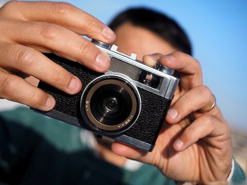 Unrecognizable man taking a picture on a retro photo camera
