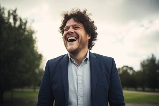 Portrait of a handsome young man with curly hair laughing outdoors.