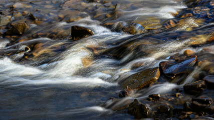 A partially frozen waterfall in late winter. Water rushes over and down the rocks at Salt Springs State Park in Montrose, PA. Heavy ice has already melted due to warmer temperatures.